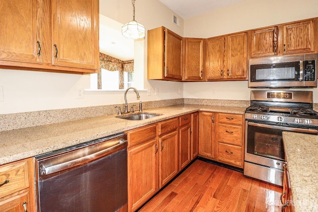 8 Staudt Ct, Franklin, NJ 08873 - kitchen featuring stainless steel appliances, wood finished floors, brown cabinets, light stone counters, and pendant lighting