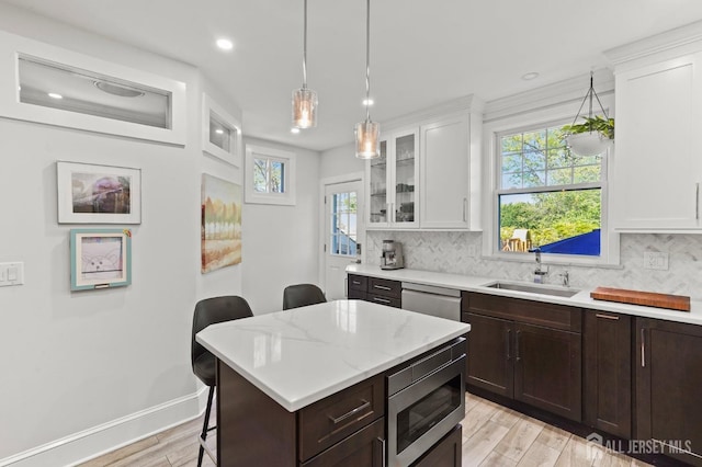 307 S 4th Ave, Highland Park, NJ 08904 - kitchen with stainless steel appliances, a sink, light wood-style flooring, a breakfast bar, and white cabinets
