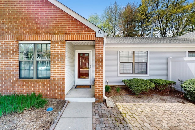 234 Wycoff Way E, Brunswick, NJ 08816 - doorway to property featuring brick siding, a shingled roof, and fence