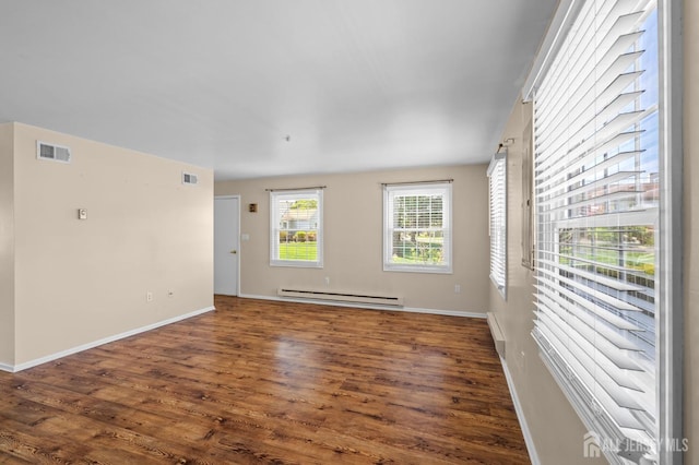 spare room with baseboards, a baseboard radiator, wood finished floors, and visible vents