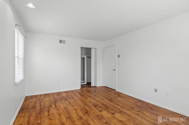 unfurnished bedroom featuring visible vents, multiple windows, and wood finished floors