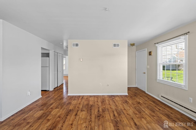 spare room featuring baseboards, a baseboard radiator, wood finished floors, and visible vents