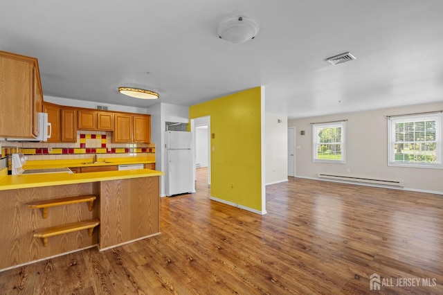 kitchen with a sink, baseboard heating, white appliances, open floor plan, and visible vents