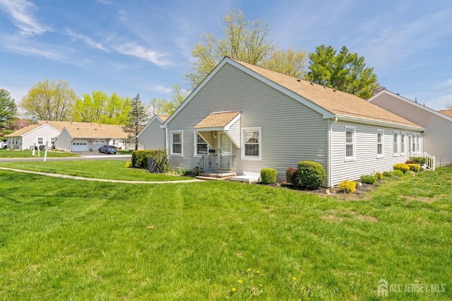 rear view of property with roof with shingles and a yard