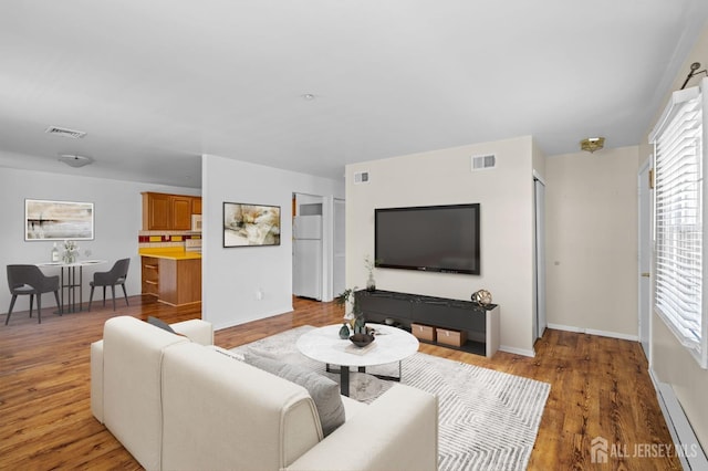 living room with baseboards, light wood finished floors, and visible vents