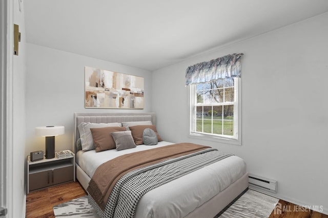 bedroom with a baseboard heating unit and wood finished floors