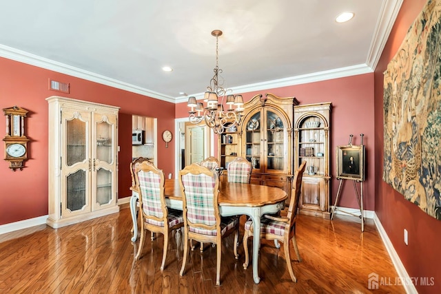 dining area featuring baseboards, an inviting chandelier, wood finished floors, and crown molding