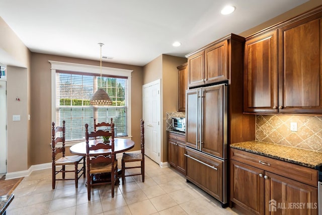 kitchen featuring visible vents, decorative backsplash, baseboards, light stone counters, and paneled built in refrigerator