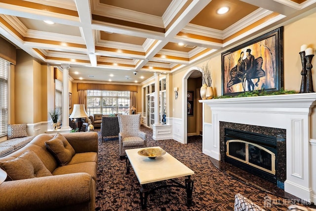 living room featuring ornate columns, a fireplace, coffered ceiling, and beamed ceiling