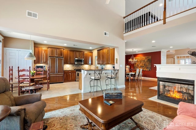 living room with baseboards, visible vents, light wood-style flooring, and a multi sided fireplace