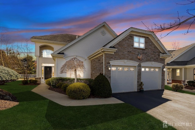 view of front of property featuring a garage, stone siding, aphalt driveway, and a lawn