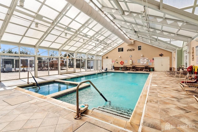 pool with glass enclosure, an indoor hot tub, and a patio