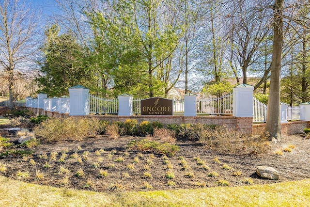 community / neighborhood sign featuring fence and a gate