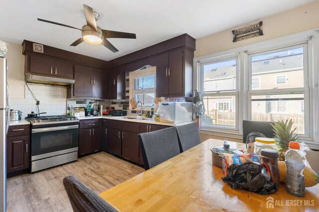 kitchen with tasteful backsplash, sink, dark brown cabinetry, gas range, and light hardwood / wood-style flooring