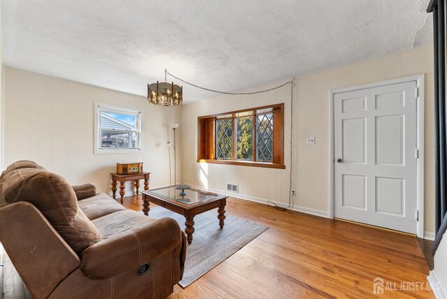 living room with a textured ceiling, light hardwood / wood-style flooring, and a notable chandelier