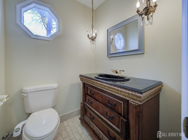 bathroom with toilet, baseboards, a chandelier, and vanity