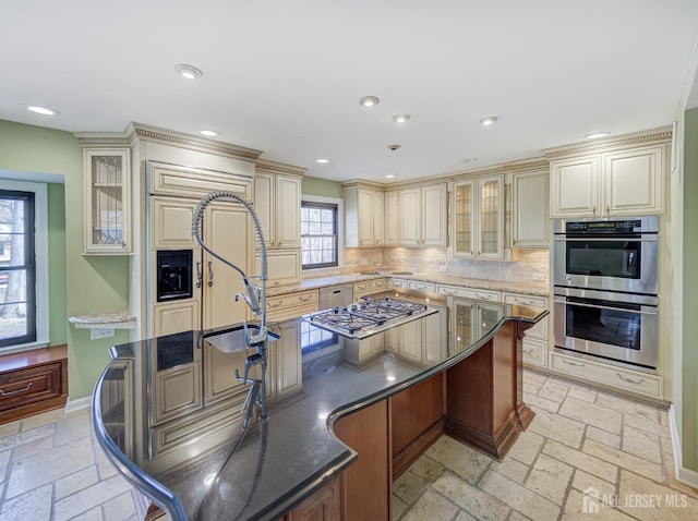 kitchen with cream cabinets, appliances with stainless steel finishes, and stone tile floors