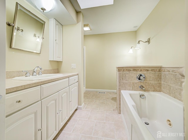 bathroom featuring a skylight, a garden tub, vanity, baseboards, and tile patterned floors