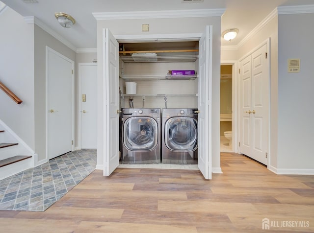 laundry area with washer and clothes dryer, visible vents, ornamental molding, wood finished floors, and laundry area