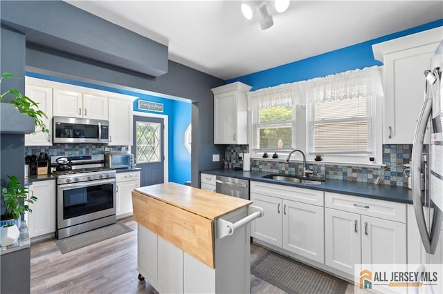 6 Hermann St, Carteret, NJ 07008 - kitchen featuring stainless steel appliances, a sink, backsplash, white cabinets, and light wood-style floors