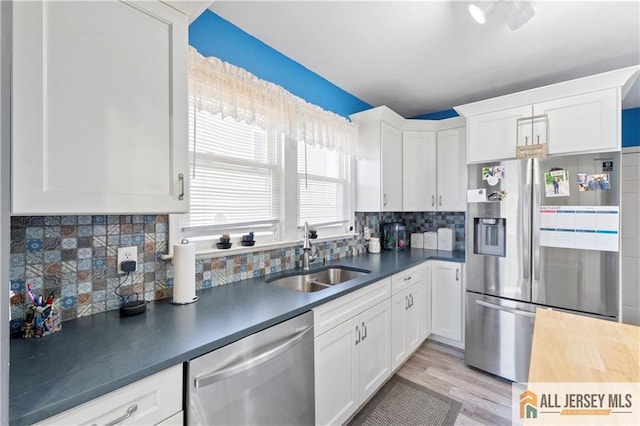 6 Hermann St, Carteret, NJ 07008 - kitchen featuring appliances with stainless steel finishes, a sink, dark countertops, white cabinetry, and decorative backsplash