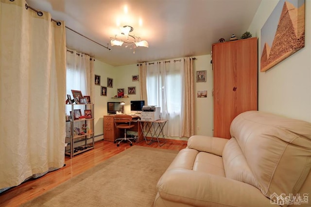 home office with a baseboard heating unit, an inviting chandelier, and wood finished floors