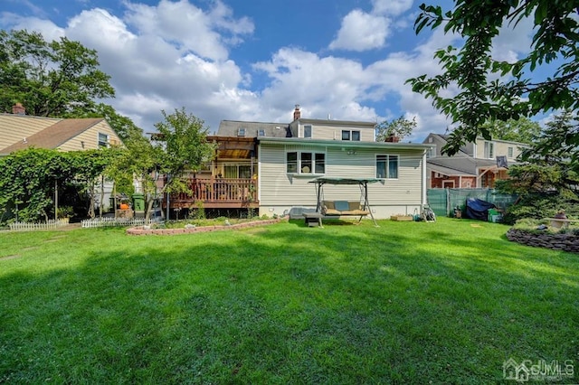 back of house featuring a deck, a chimney, a yard, and fence