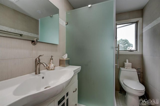 full bath featuring toilet, vanity, a shower with shower door, tile patterned floors, and tile walls