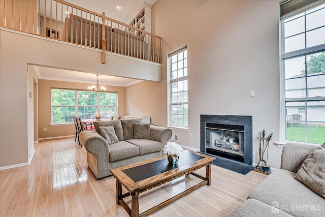 36 Jared Blvd, South Brunswick, NJ 08824 - living area featuring a towering ceiling, a chandelier, light wood-style flooring, a glass covered fireplace, and crown molding