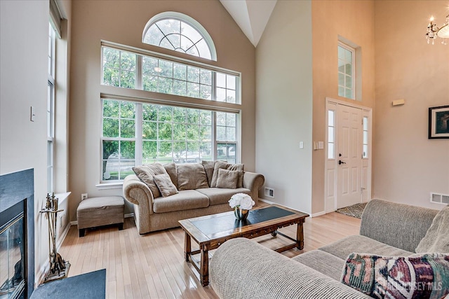36 Jared Blvd, South Brunswick, NJ 08824 - living room with a chandelier, light wood-type flooring, high vaulted ceiling, and a glass covered fireplace