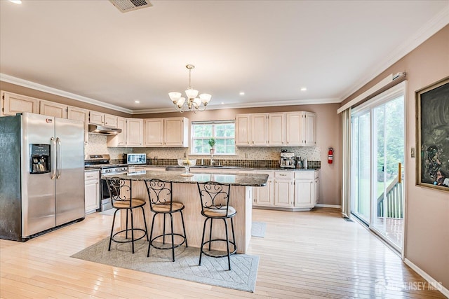 36 Jared Blvd, South Brunswick, NJ 08824 - kitchen featuring appliances with stainless steel finishes, under cabinet range hood, a kitchen bar, a chandelier, and decorative backsplash