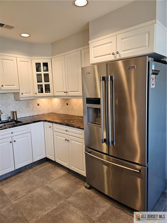 kitchen with tasteful backsplash, high end refrigerator, sink, and white cabinets