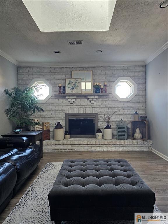 living room with ornamental molding, hardwood / wood-style floors, and a textured ceiling