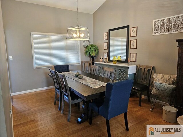 dining area featuring an inviting chandelier, lofted ceiling, and hardwood / wood-style floors