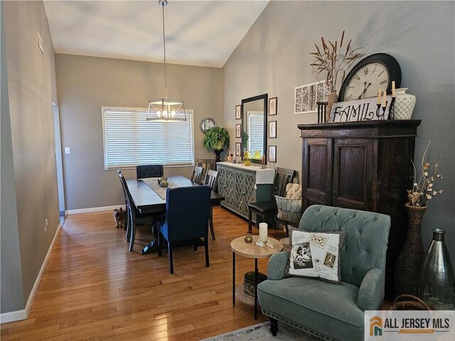 dining room featuring an inviting chandelier, lofted ceiling, and light wood-type flooring