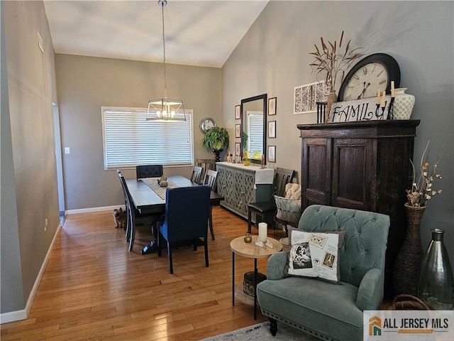 dining room featuring baseboards, high vaulted ceiling, light wood finished floors, and an inviting chandelier