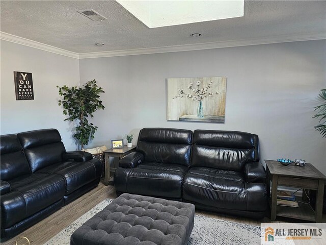 living room featuring ornamental molding, light hardwood / wood-style floors, and a textured ceiling