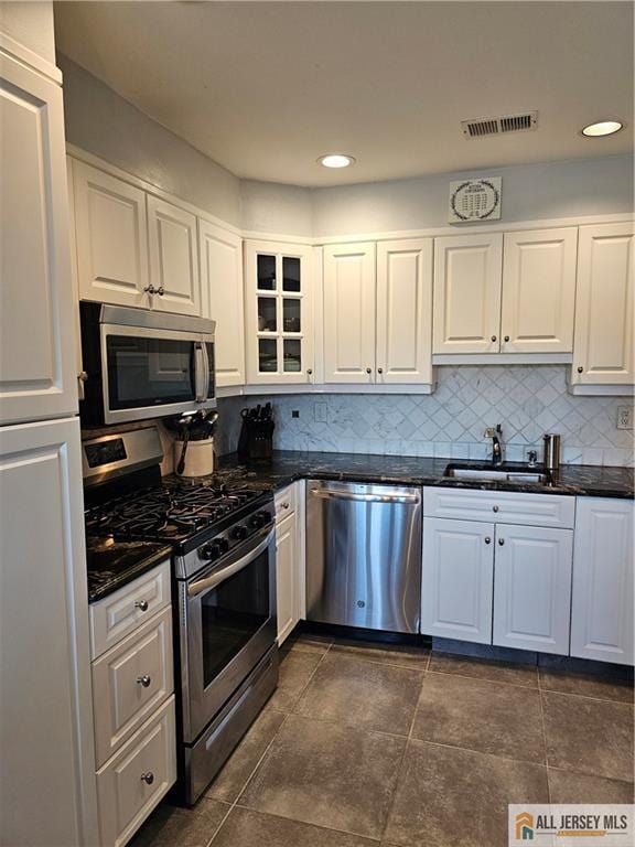 kitchen featuring stainless steel appliances, tasteful backsplash, visible vents, glass insert cabinets, and white cabinets