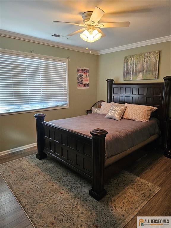 bedroom with hardwood / wood-style floors, crown molding, and ceiling fan