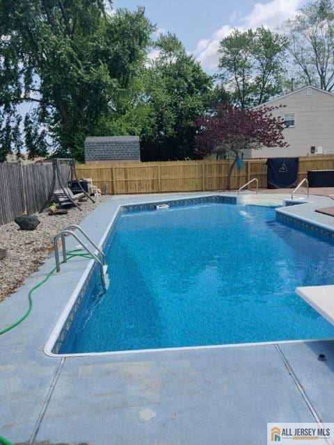 view of swimming pool with a fenced in pool, a fenced backyard, and a diving board