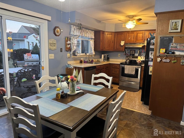 kitchen with under cabinet range hood, light countertops, brown cabinets, stainless steel appliances, and a sink