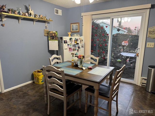 dining space featuring visible vents, a textured ceiling, a baseboard heating unit, and baseboards