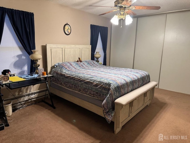 bedroom featuring a ceiling fan, carpet floors, and a textured ceiling