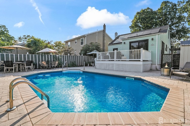 view of pool featuring a patio, a wooden deck, and an outdoor structure