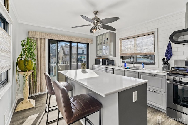 kitchen with a kitchen bar, sink, a center island, light wood-type flooring, and stainless steel range with gas stovetop