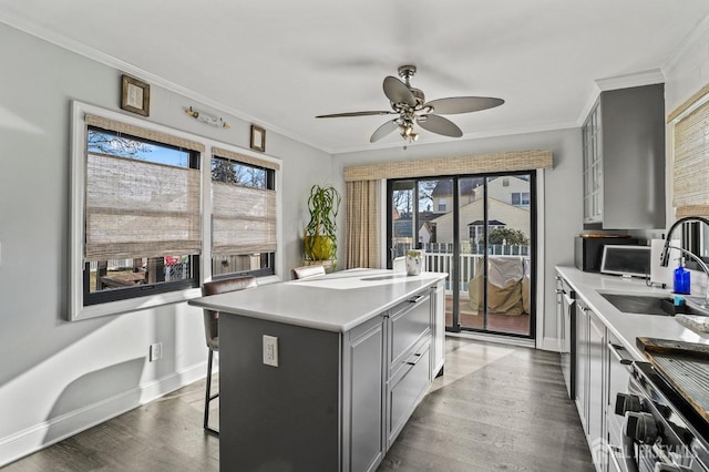 kitchen featuring wood-type flooring, a kitchen breakfast bar, crown molding, a center island, and gray cabinets