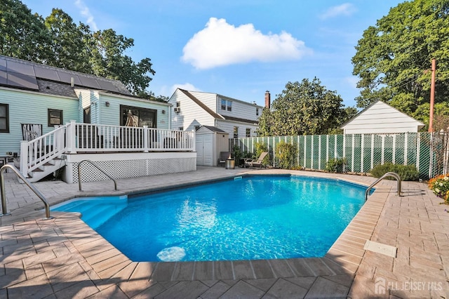 view of swimming pool featuring a shed, a deck, and a patio area