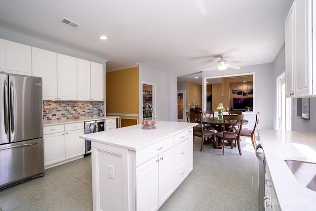 kitchen featuring stainless steel appliances, wine cooler, light tile patterned floors, backsplash, and light countertops
