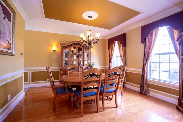 dining room with a tray ceiling, a chandelier, light wood-style floors, and ornamental molding