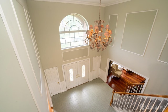 entrance foyer with a chandelier, crown molding, a high ceiling, and tile patterned floors